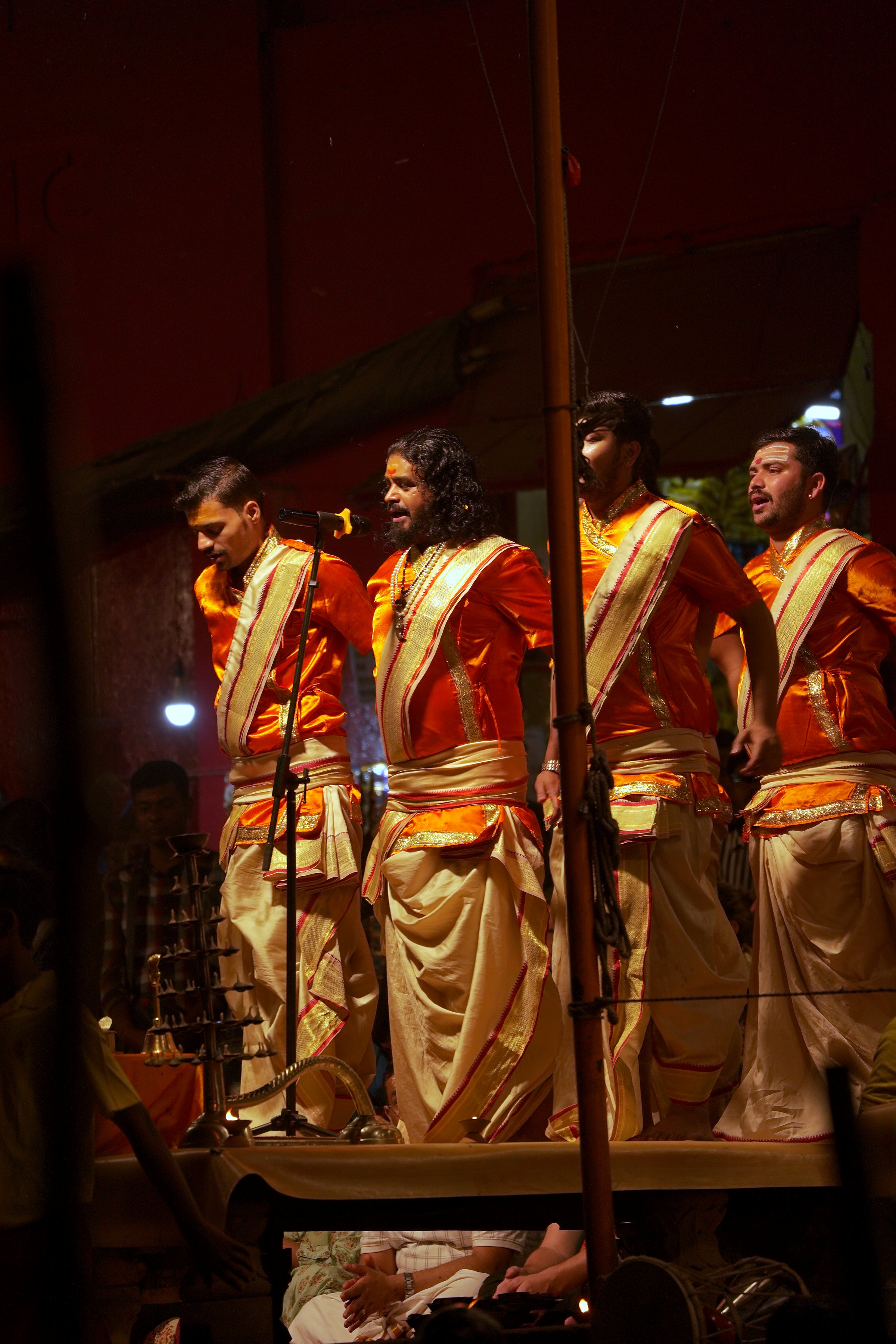 Priests in saffron on the aarti platform at night